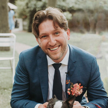Christer in a blue suit, smiling, in a garden. The top of Cactus's head is just in frame.